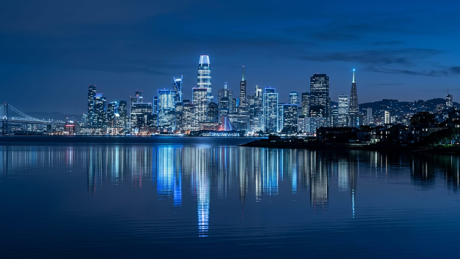 The San Francisco skyline at blue hour seen across the bay, office towers lit against a deep navy sky