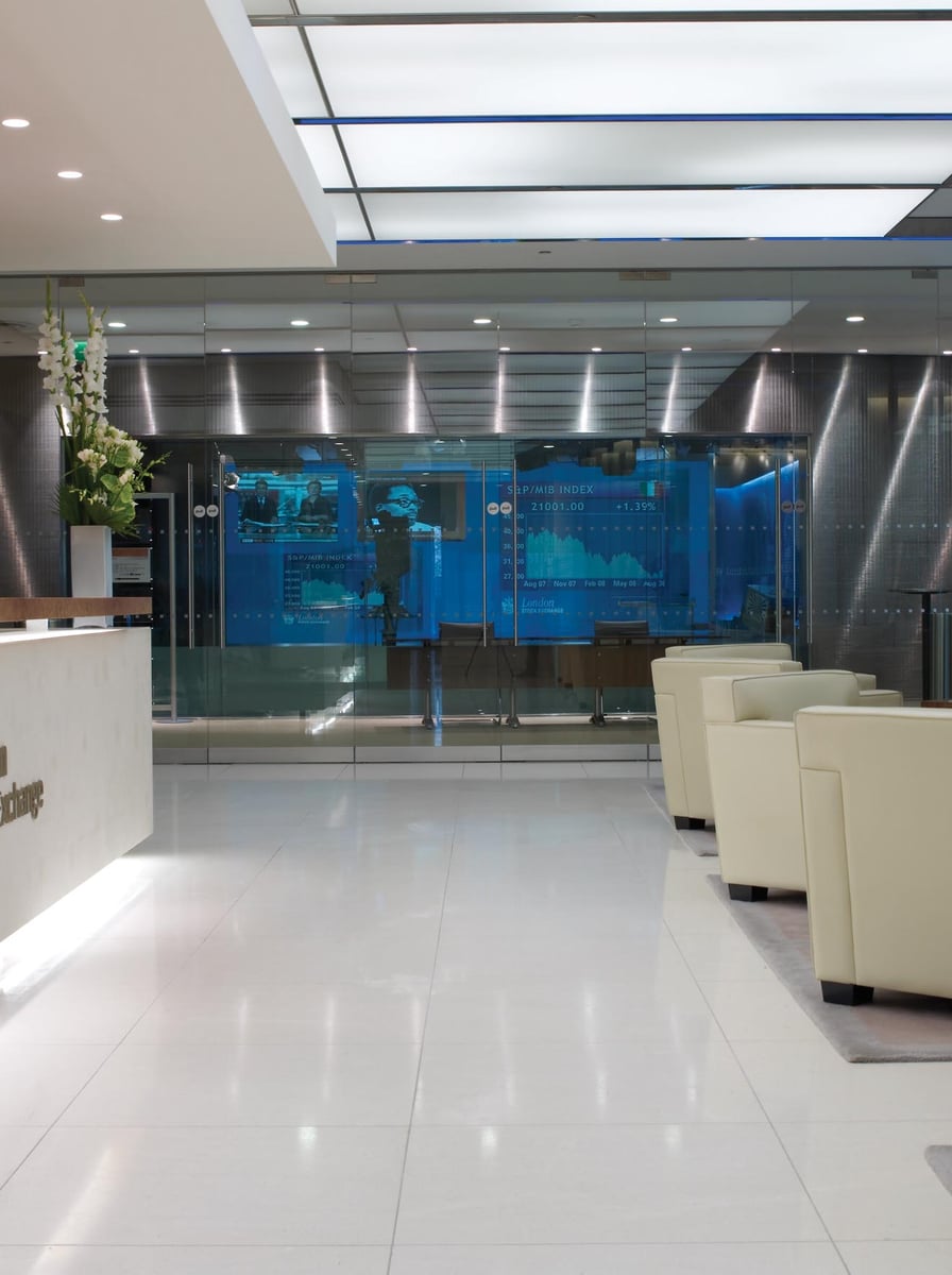 A stock exchange trading floor with large display screens showing market indices and price movements