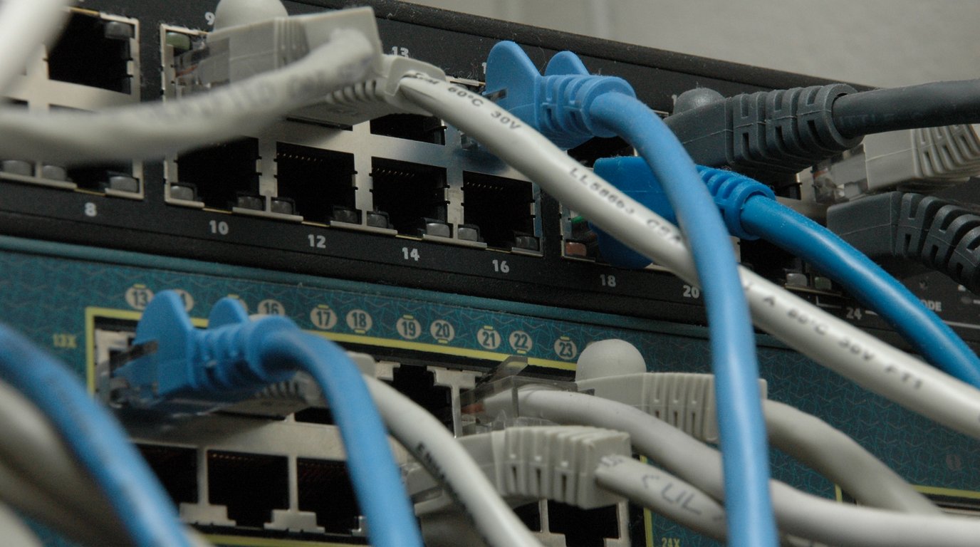Rows of network switches with blue status lights in a data centre