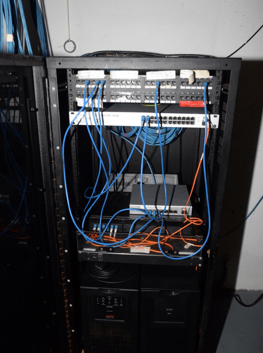 A vertical server rack view showing fiber-optic and ethernet cable bundles feeding into networking equipment.