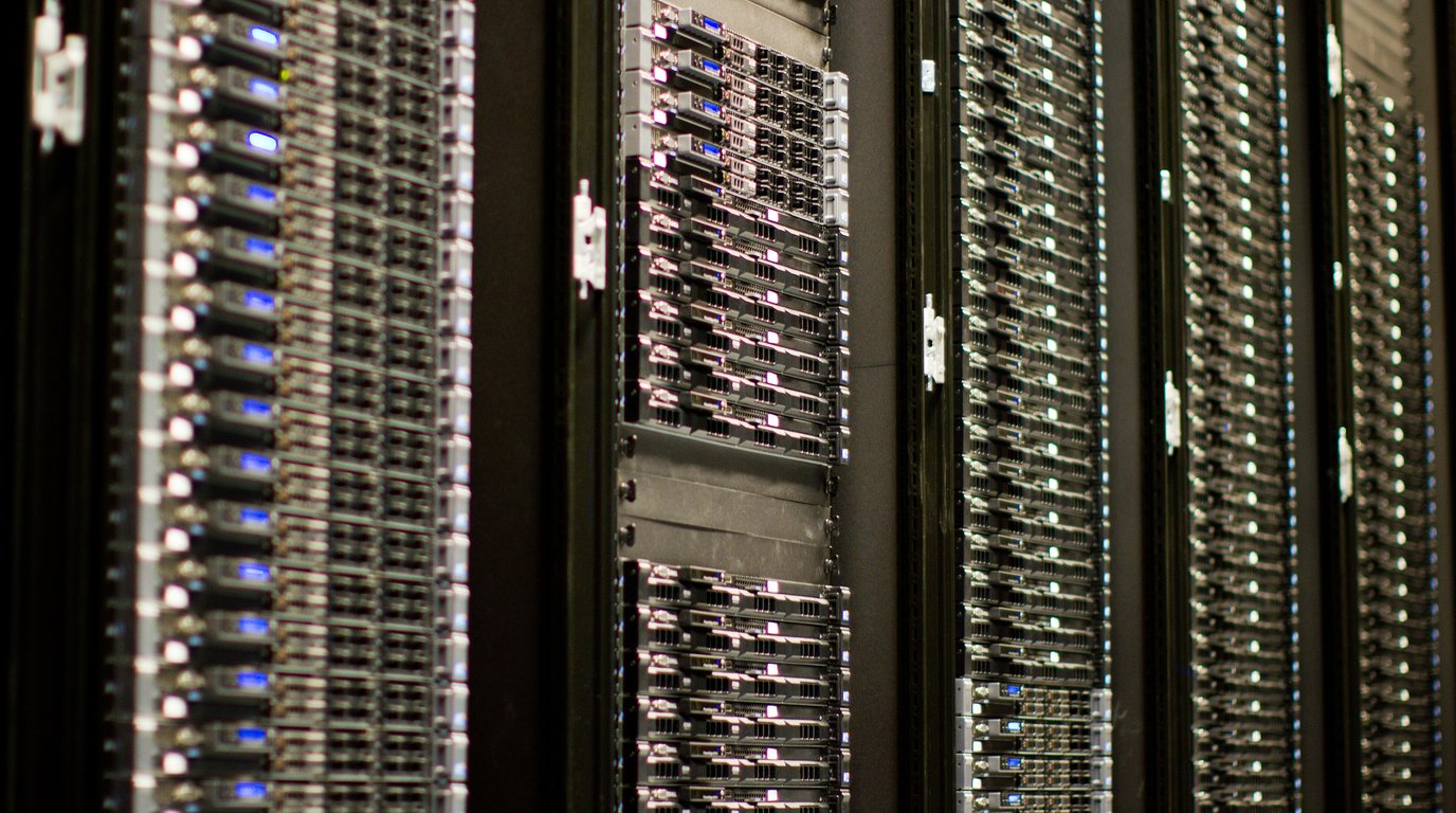 A close, angled view down a row of illuminated server racks with status lights glowing, stretching into the distance.