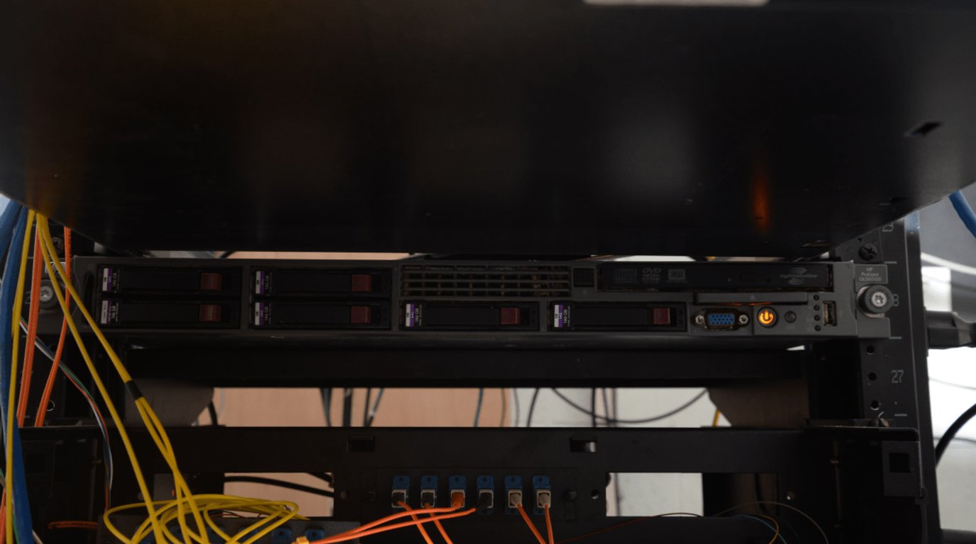 A dense patch panel and network switch with blue and grey cables routed and bundled across multiple rows of ports.